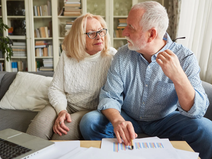 Older couple reviewing retirement plan documents and a portfolio performance chart at home in Indianapolis